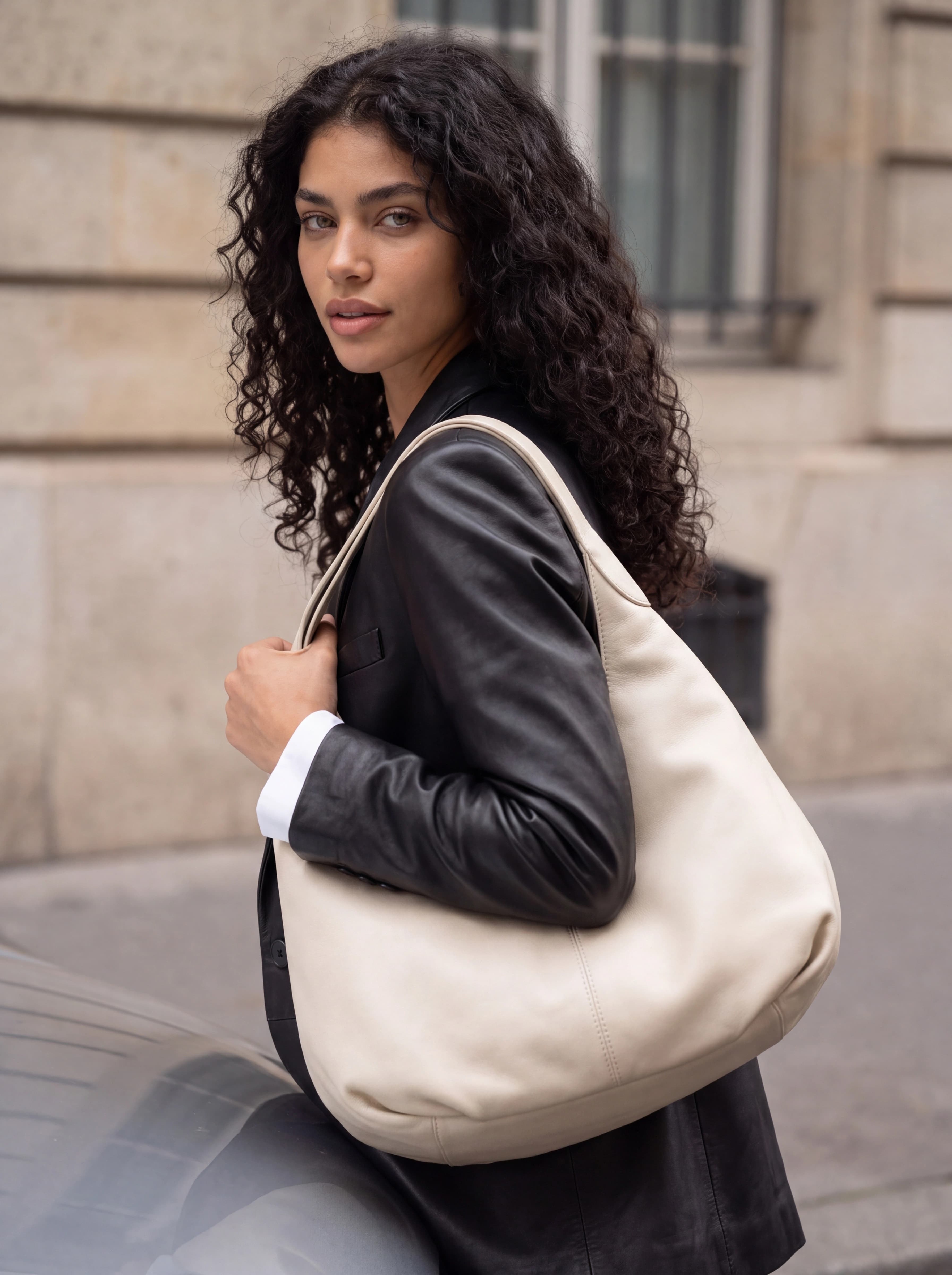 A generated model on the street with a cream leather shoulder bag, delivered with its identity paperwork